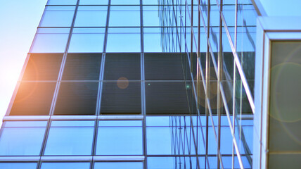 Modern architecture with sun ray. Glass and steel facade on a bright sunny day with sunbeams on the blue sky. Economy, finances, business activity concept.