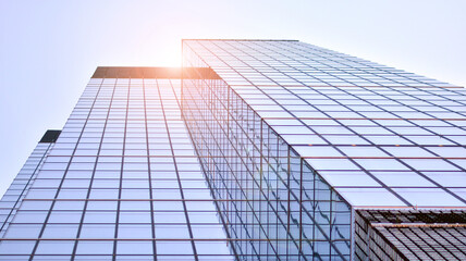 Modern architecture with sun ray. Glass and steel facade on a bright sunny day with sunbeams on the blue sky. Economy, finances, business activity concept.