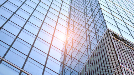 Modern architecture with sun ray. Glass and steel facade on a bright sunny day with sunbeams on the blue sky. Economy, finances, business activity concept.