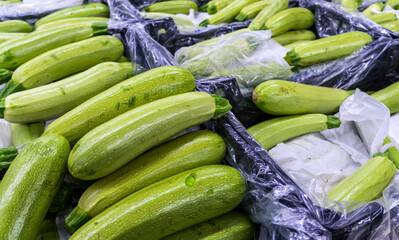 Green, white zucchini in black boxes. Vegetables in the supermarket