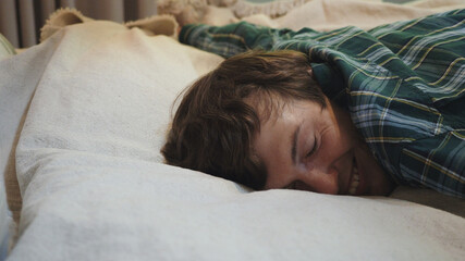 Exhausted young man falling asleep on bed, feeling no energy after hard working day. Businessman flopping down on bed, needs rest at home.