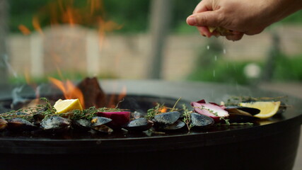 Man squeezing lemon on seafood on grill. Chef cooking mussels on grade