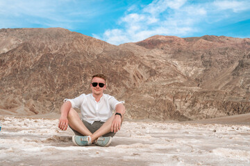 Fototapeta na wymiar A young blond man visits a dried up salt lake A pool of bad water in Death Valley