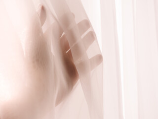 closeup of hand behind transparent pink curtain
