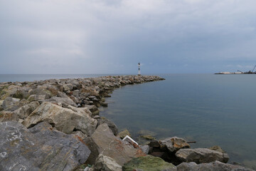 Fototapeta na wymiar lighthouse on the scythe of stones in the sea