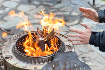 a man warms his hands by the fire. only hands and fire in the frame