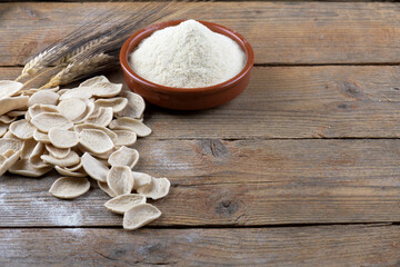 Fresh dry homemade italian pasta strascinati with durum wheat flour in a clay bowl on a natural wooden background with copy space, made in Puglia, Italy