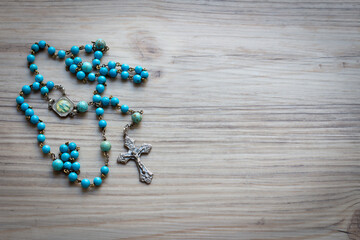 Blue rosary on wood with copy space - obrazy, fototapety, plakaty