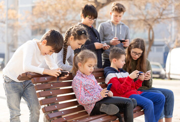 Group of children communicate using smartphones in the playground. High quality photo