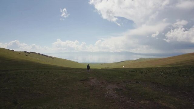 A hiker walking toward Songkul lake in Kyrgyzstan