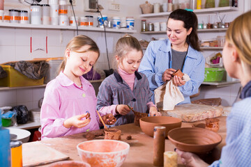 .Smiling students are trying to make the first works of clay in the classroom for arts and crafts
