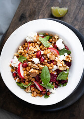 Delicious lentil salad with beets, radishes, pomegranate seeds, arugula and goat cheese. Refreshing legume and vegetable salad. Food photography