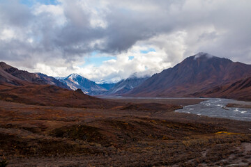 dramatic autumn landscape of snowcapped mountain ranges and peaks inside DEnali National park .