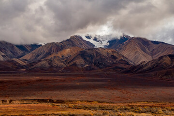 dramatic autumn landscape of snowcapped mountain ranges and peaks inside DEnali National park .