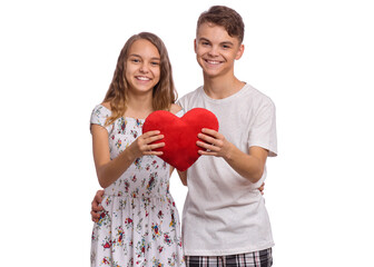 Happy teen boy and girl standing together, holds plush heart in hands. Hugging smiling teenagers with symbol of love, family, hope. Portrait of sweet young couple in love. Friendship and love concept - 433704878
