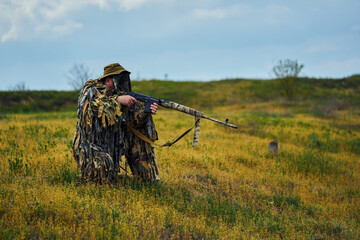 Airsoft player in camouflage military uniform holds a rifle in his hands