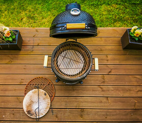 A kamado type barbeque grill with its accessories standing on a living house terrace. With cast...