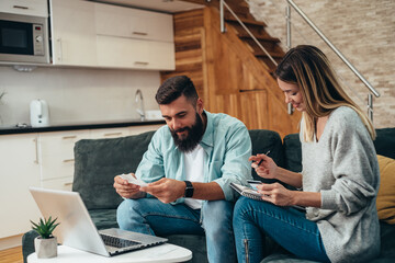 Young beautiful couple using a laptop while going trough finances at home