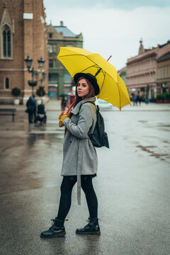 Young beautiful woman holding a yellow umbrella outside on a rainy day