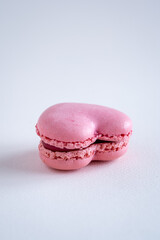 A single strawberry flavoured heart-shaped French macaron, copy space on neutral background