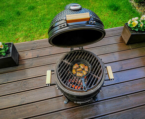 A kamado egg type barbeque grill with a pan with a pan with roast beef standing on a living house...