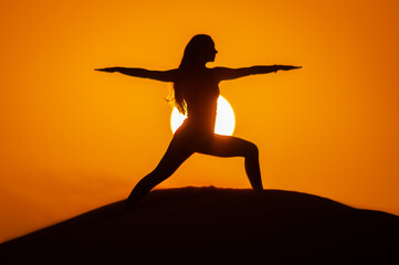 Fototapeta na wymiar Silhouette of a young woman doing yoga pose at sunset
