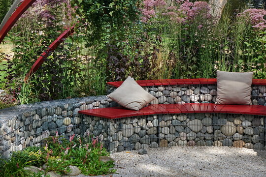 Designed Backyard Garden Patio and Outdoor Party Place. Modern Garden Design and Landscaping. Round Bench Made from Gabions with Wooden Seat. Landscaped Family Resting Area with Fireplace.
