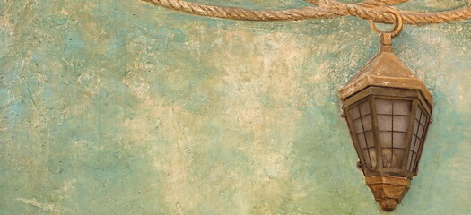Vintage Wall Background Or Texture Decorated With Painted Rope And Real Old Copper Anchor Nautical Oil Lantern Or Retro Lamp. Graffiti Wall Abstract Background Texture.