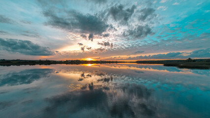 Beautiful clouds reflected on surface lake water at the sunrise. Scenic nature background