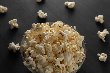 Palomitas de maíz en un recipiente con palomitas tiradas en la mesa de color negro