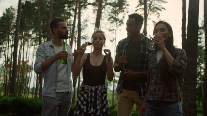 Young woman eating french bean outside. Relaxed fellows drinking beer and wine