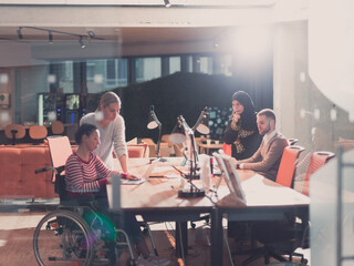 Disabled businesswoman in a wheelchair in modern coworking office space. Colleagues in background. Disability and handicap concept. Selective focus