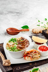 Asian noodle soup. Ramen with beef, tofu and vegetables in white plate on concrete background. Close up. 