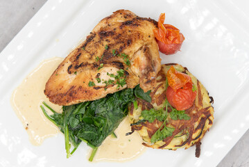 Overhead view of roasted chicken breast served with spinach and hash to fulfill that big appetite