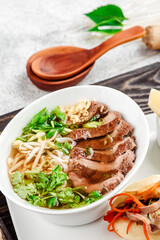 Asian noodle soup. Ramen with beef, tofu and vegetables in white plate on concrete background. Close up. 