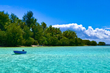 small blue boat close to Moorea motu in shallow water