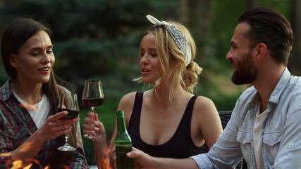 Cheerful men and women drinking alcohol outside. Friendly people saying toasts
