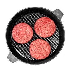 Raw Minced Steak Burgers in Grill Pan Isolated On White Background, Overhead View. Uncooked Beef Ground Meat Patties for Grilling. Burgers for BBQ Grill In Cast Iron Girdle, Top View.