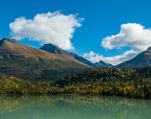 mountain and autumn foliage of trees reflection on a calm lake in the Kenai peninsula in Alaska.