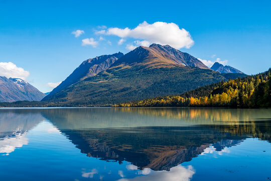 mountain and autumn foliage of trees reflection on a calm lake in the Kenai peninsula in Alaska.