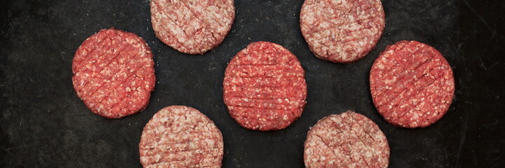 Raw Minced Steak Burgers from Beef and Pork Meat on Black Background, Overhead View. Raw Ground Beef, Round Patties for Cooking Homemade Burger On BBQ Grill, Top View