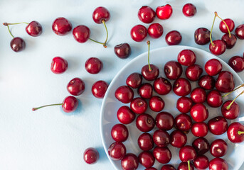 Sweet cherry in a plate close up on a blue background. Top view.