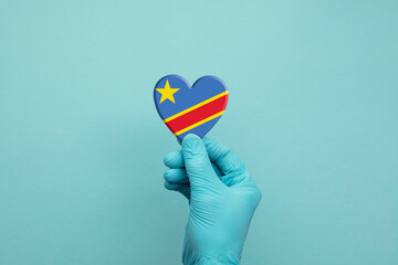Hands wearing protective surgical gloves holding Congo flag heart