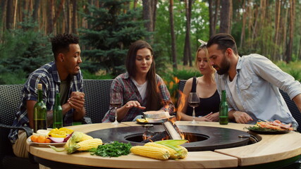 Friends preparing fish at bbq grill outdoors. Fellows discussing cooking process