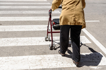 Rollator pushed by an elderly woman with mobility difficulties, unrecognizable with copy space.