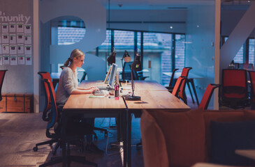 Disabled businessman in wheelchair working overtime alone at his desk in an office late at night 