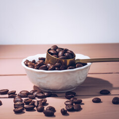 Coffee beans in a white plate on a wooden background. Coffee content, coffee shop.