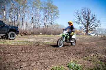A kid rides his dirt bike on an out door track.