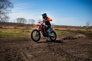 Dirt biker does a wheelie as he comes out of a corner.