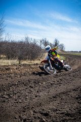 Fototapeta na wymiar Motocross rider rides an orange dirt bike on a race track.